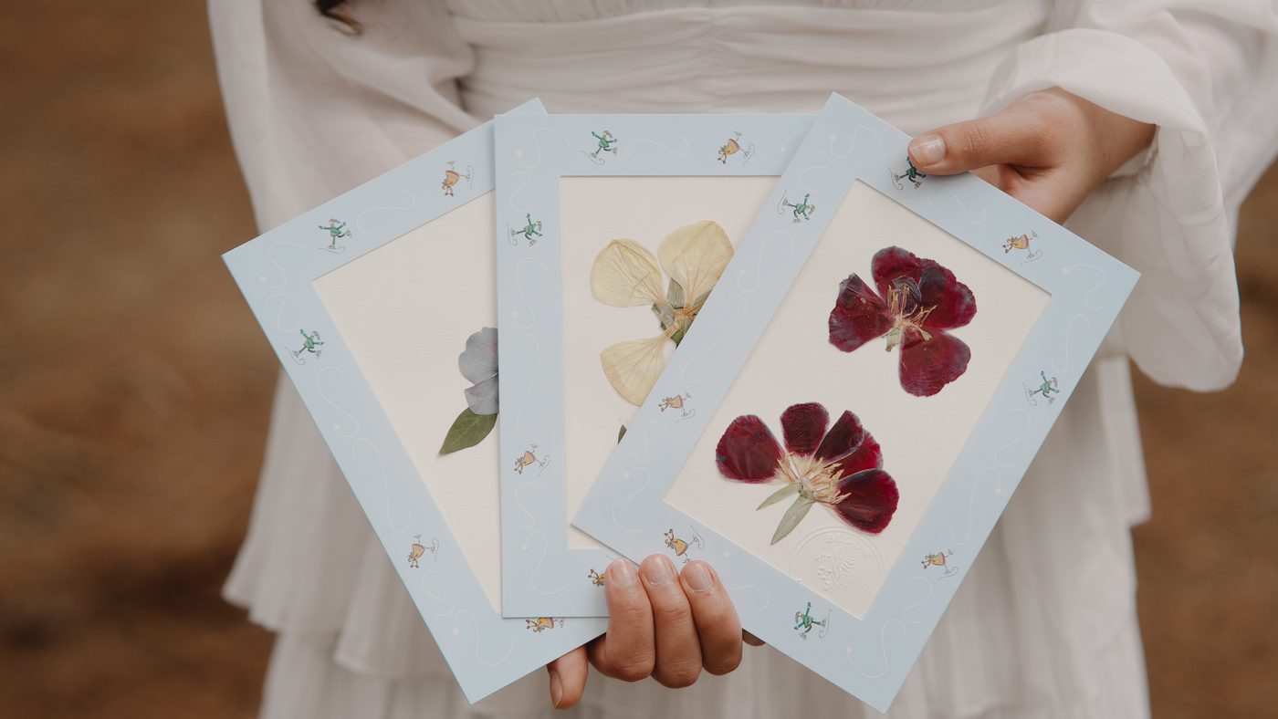 Tarjetas con flores prensadas sostenidas en las manos